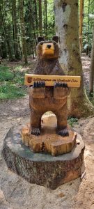 Geschnitzter Bär mit einem Willkommen im Stadtwald-Schild